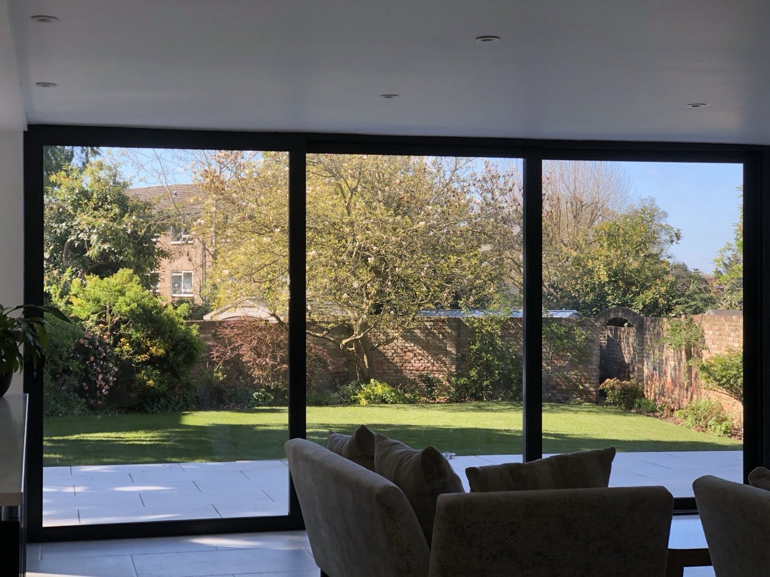 A crisp paved terrace and lawn, framed by a walled garden.